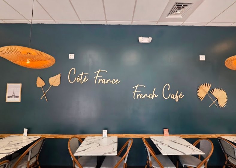 La salle du Côté France French Café à Tampa, enseigne murale et tables en marbre
